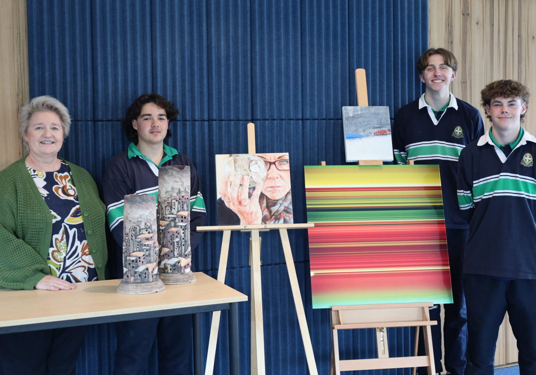 Flanagan Art Prize coordinator Wendy Sheridan and students Leo Card, Gabe Bristow and Will Sheehan with some winning works from previous years.